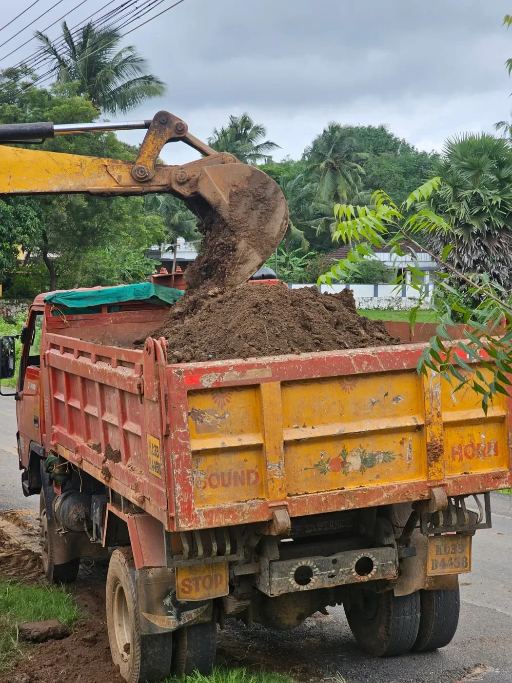 Excavator loading a tipper truck during site clearance.